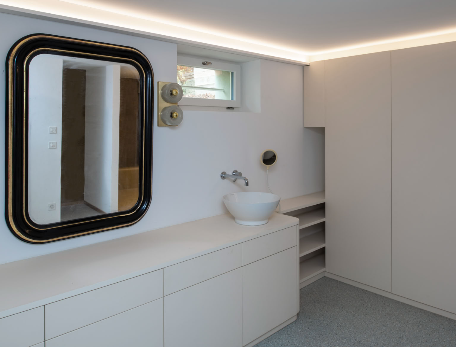 Dressing moderne avec un grand miroir encadré, un lavabo blanc, des armoires blanches et un éclairage encastré au plafond.