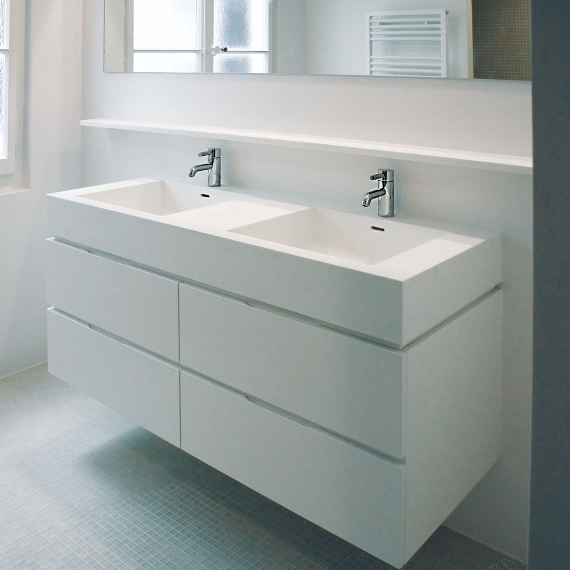 Double lavabo moderne avec tiroirs blancs dans une salle de bain lumineuse