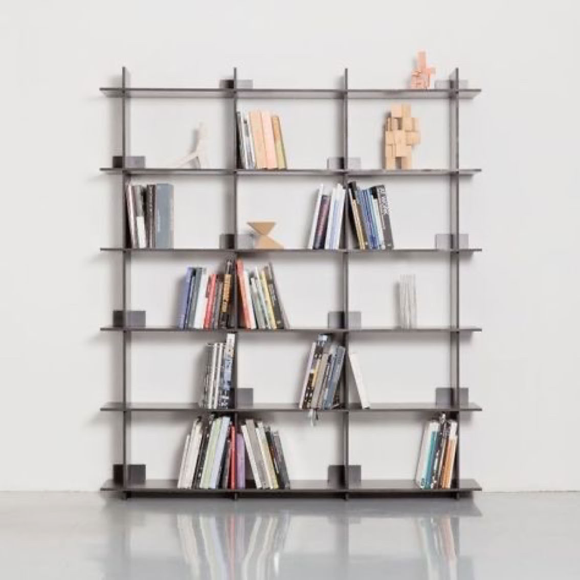 Étagère moderne avec plusieurs livres et objets décoratifs sur un fond blanc.